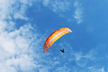 paraglider in a blue cloudy sky
