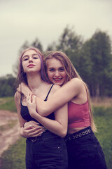 Fototapeta premium Two teenage girls with long hair on a walk hug each other.