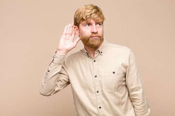 young blonde man looking serious and curious, listening, trying to hear a secret conversation or...