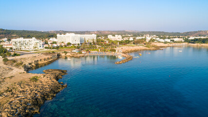 Aerial bird's eye view of Green bay in Protaras, Paralimni, Famagusta, Cyprus. Famous tourist attraction diving location rocky beach with boats, sunbeds, sea restaurants, water sports from above.