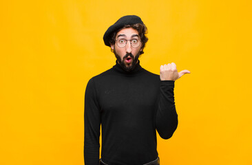young french artist man looking astonished in disbelief, pointing at object on the side and saying...