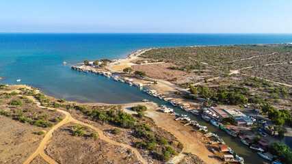 Fototapeta na wymiar Aerial bird's eye view Liopetri river to sea (potamos Liopetriou), Famagusta, Cyprus.Fjord landmark tourist attraction fishing village with colourful boats moored on banks at Kokkinochoria, from above