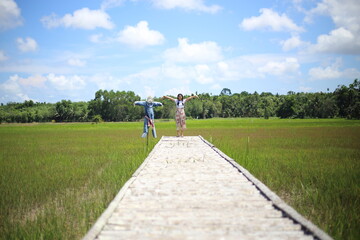 A woman standing on a wooden bridge in a rice field