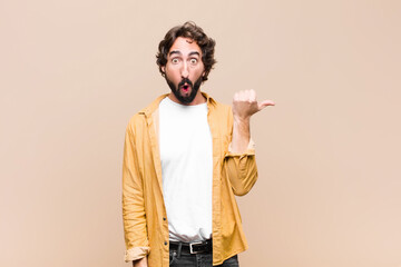 young crazy cool man looking astonished in disbelief, pointing at object on the side and saying...