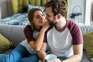 Beautiful young couple drink coffee hold cup, sitting on a sofa