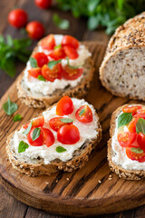Fototapeta na wymiar Bruschetta with fresh ricotta cheese and cherry tomatoes on wooden board decorated with basil leaves. Closeup view. Italian antipasti, healthy savory toast with cheese and tomato