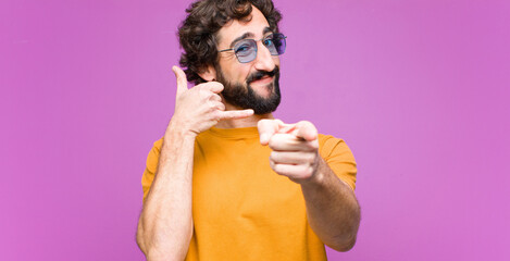 young crazy cool man smiling cheerfully and pointing to camera while making a call you later...