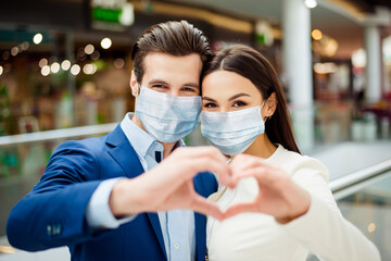 Fototapeta na wymiar Close-up portrait of lovely her she lovely woman with his he boyfriend in suit wearing sterile mask showing heart sign together forever walk in modern mall covid19 sars outbreak protection