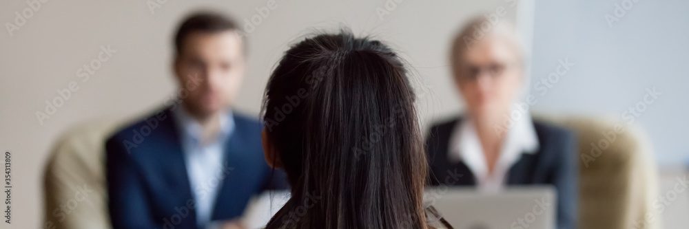 Sticker rear view woman applicant during job interview, out of focus two hr managers interviewing company po