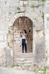 Young female Asian tourist traveling in the stone chateau, taking photograph of her surrounding