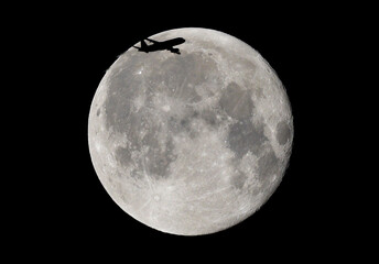 Księżyc dzień po pełni i przelatujący samolot na tle tarczy.