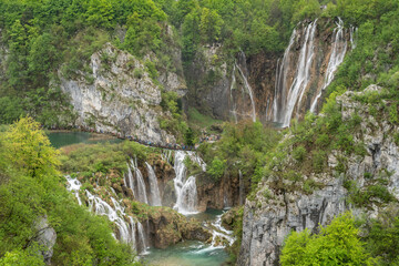 Croatia national park waterfall with tourist walking in line over the waterfall in distance