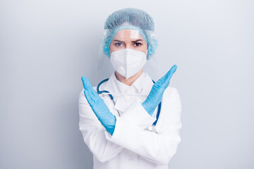 Fototapeta premium Photo of beautiful lady doc work covid bacteria crossing palm don't let colleagues step into dangerous zone wear gloves mask coat facial plastic surgical cap isolated grey color background