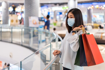 woman shopping with bag at mall and her wearing medical mask for prevention from coronavirus (Covid-19) pandemic. new normal concepts