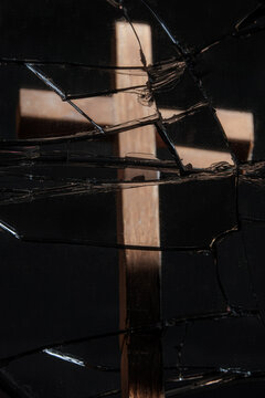 Reflection of wooden cross on broken mirror