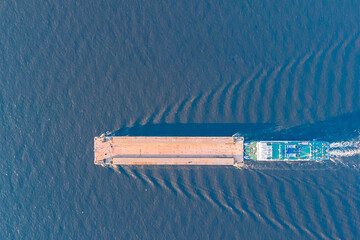 View from a drone of a river tugboat moving cargo barge to navigate the Volga river.
