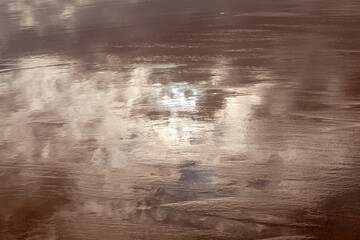 reflection of the sun in the wet sand on a cloudy day