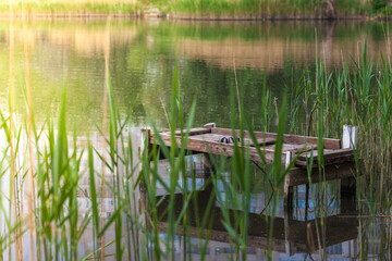 Pond in a city park with a bridge for fishermen. Reflection of houses in the water of a lake or river.