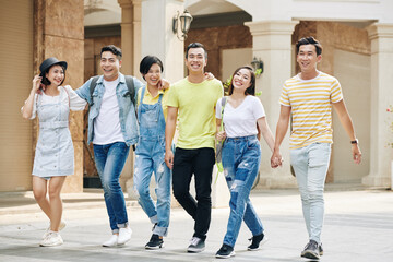 Naklejka premium Group of happy young Asian people walking in the street on sunny day