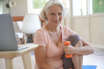 Senior woman doing fitness exercises with virtual class