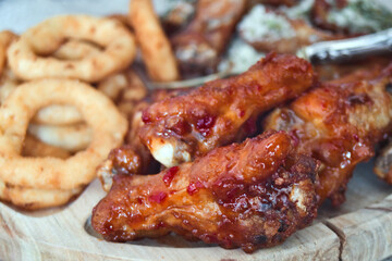 Delicious and unhealthy fast food - deep fried chicken wings with sweet chili sauce and parmesan with basil served with onion rings