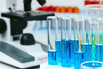 Microscope and test tubes on table in laboratory, close up