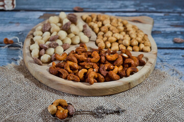 Variety of delicious nuts as heathy vegan appetizer - brazil nuts with chili, walnuts with garlic, sweet caramelized almond with cinnamon and macadamia on a rustic wooden board