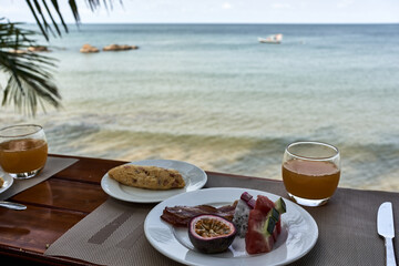 Healthy breakfast on a restaurant's wooden counter in front of the sea. Concept of vacation and leisure. Close up.