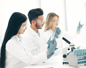 close up. woman scientist looking at the tube with liquid