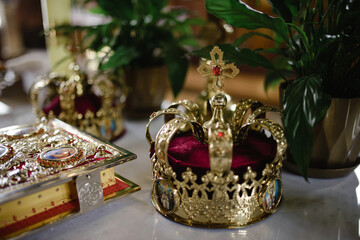 golden crown with gemstones on red napkin on altar in church. traditional wedding ceremony, religion