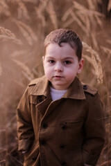 Cute little boy 
standing in a field with tall grass and smile.