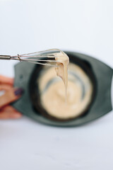 stylist kneads hair dye in a black container close up