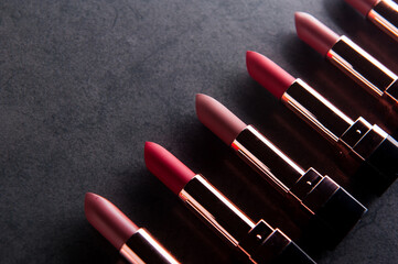 lipsticks lie on a dark surface. Cosmetic theme