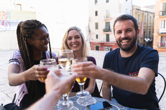 Friends drinking drinks on the terrace of a bar. The camera toasts with his friends happily. New normality concept