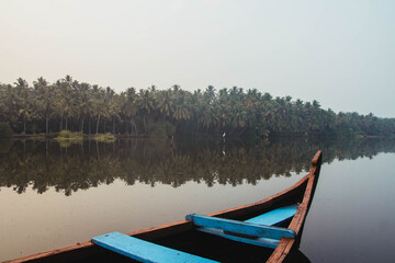 Fototapeta premium Wooden boat on the backwater canals on a background of tropical forest with palm trees. Copy, empty space for text