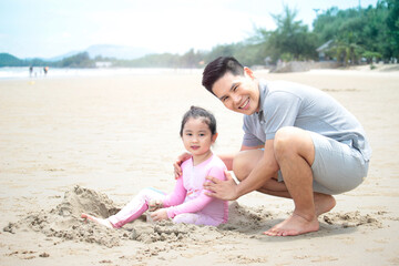 Fototapeta premium Happy family, father and little daughter having fun and spending time togetheron summer vacation, dad playing with kid on tropical beach