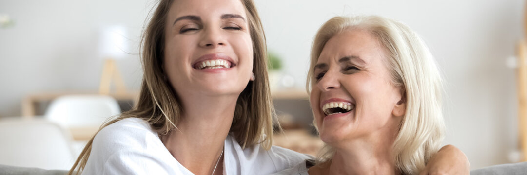 Horizontal banner for website header design laughing grown up daughter hug mature 60s mother, beautiful positive women spend time together chatting enjoy communication joking having fun close up photo
