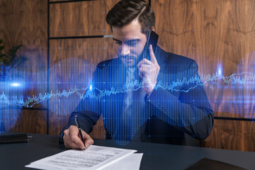 A man in office signing papers while talking phone and stock market graph and chart hologram. Double exposure. Formal wear.