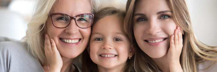 Little girl her young mother and mature grandma portrait. Multi generational women faces smiling...