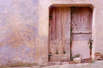 Old wooden door against a pastel color wall closes the entrance to an abandoned house. Sos del Rey Catolico, Aragon, Spain