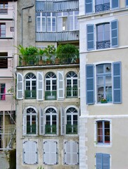 Obraz premium Facades of buildings in the city. High floor windows with pastel blue shutters, balconies with outdoor plants. Typical french houses. Pau, France
