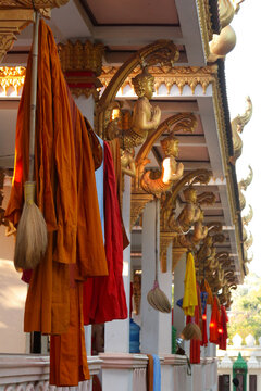 Open hallway decorated with golden buddha images and used to hang and dry typical monks clothes in Siamese Lao PDR, Southeast Asia