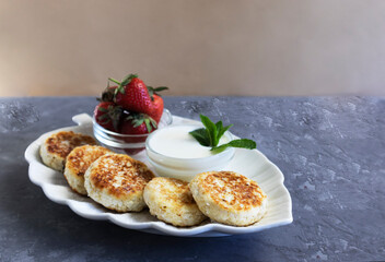 cheese pancakes or sirniki, syrniki traditional breakfast in Russia and Ukraine, delicious dessert with sour cream and fresh fruits, horizontal orientation, selective view