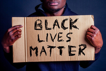Man holding a cardboard sign reading Black Lives Matter