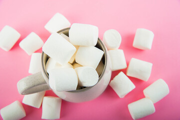 Marshmallows close-up and copy space on a pink background. Marshmallows in an earthenware mug.
