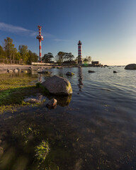 Obraz premium Shepelevsky lighthouse at the tip of the Karavaldai peninsula in the Leningrad region on a summer evening at sunset among a stone beach.