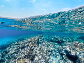 Fototapeta premium Split underwater view of rocks and blue sea in Sardinia