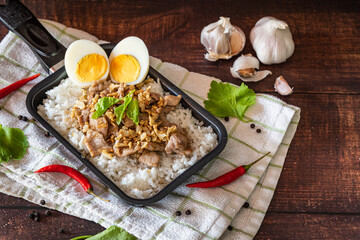 Stir fried pork with garlic and boiled egg as traditional Thai food for quick meal on wooden table