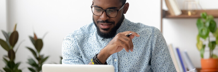 Millennial African employee sit at office desk using pc look at screen read e-mail, received good...