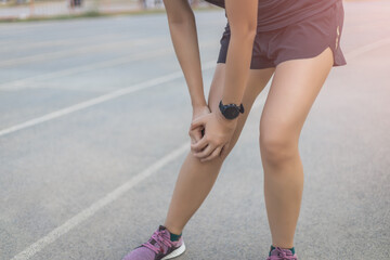 Runner woman injured after running. She is touching on knee that is painful area.